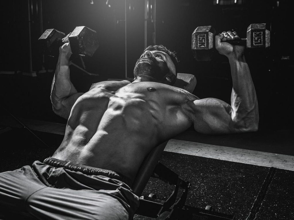 Fitnessathlete voert dumbbell oefening uit voor kracht opbouwen met halters en dumbbells in de sportschool
